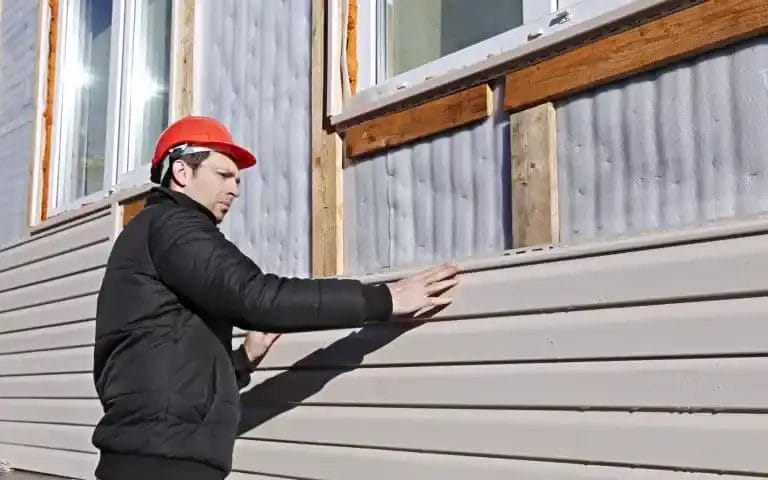 A worker installing a type of siding on a house.