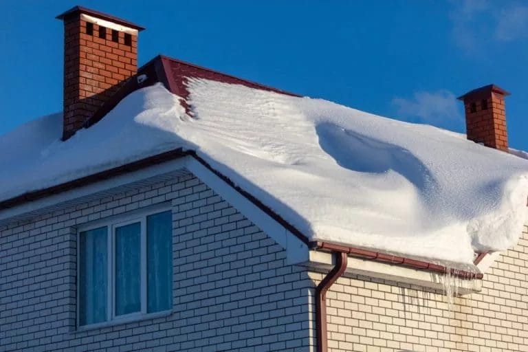 A brick house with snow settled on a roof.