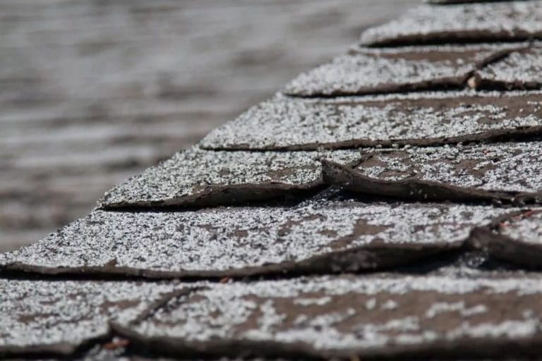 Old worn out asphalt shingles on the roof of a residential home.
