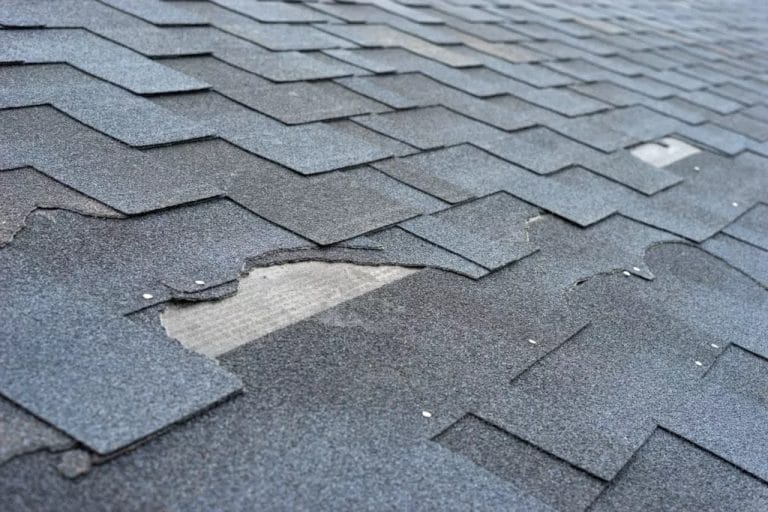 Torn and missing roof shingles on a home
