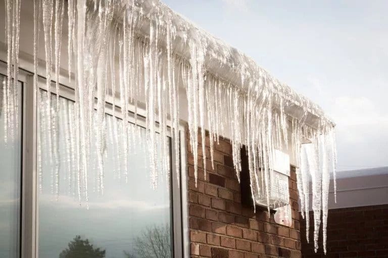 An ice dam with icicles on a residential roof.