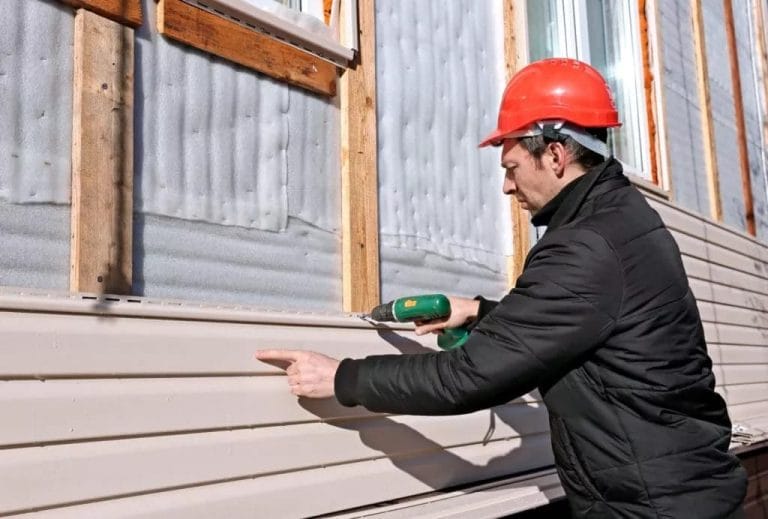 A worker installing vinyl siding on a home after the homeowner considered replacing vinyl siding and weighed the pros and cons